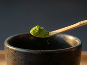 Macro del chashaku de bambu de Matcha Colors midiendo un gramo de matcha verde sobre un cuenco oscuro - campaña IA