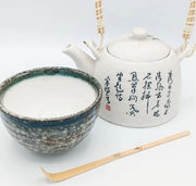 Cuchara chashaku de bambú artesanal junto a cuenco y tetera japonesa de cerámica
