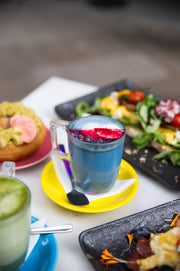 Latte azul de Matcha Colors en mesa de restaurante con platos de comida - hostelería