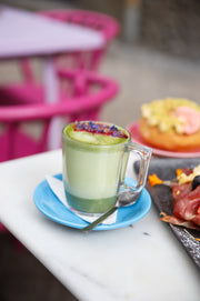 Latte verde de Matcha Colors con donut en una terraza con sillas rosas