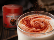 Macro del polvo rojo de Rooibos Powder de Matcha Colors formando un remolino en leche vaporizada - campaña IA