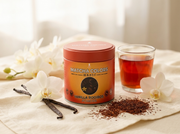 Lata de Vanilla Rooibos Powder de Matcha Colors entre orquídeas blancas, vainas de vainilla y té rooibos con luz crema suave - campaña IA